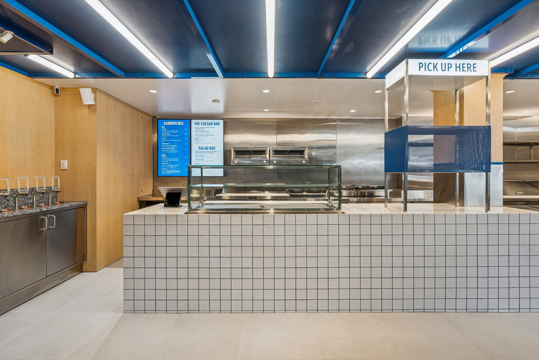 Cross Section servery counter with white tiling and the blue 'Pick Up Here' canopy